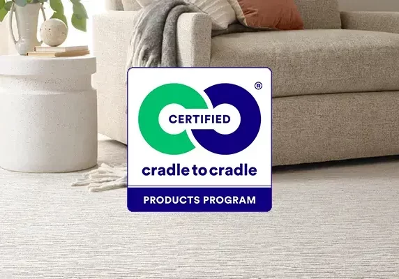 Cradle to Cradle Certified Products Program" logo overlaid on a living room scene featuring a light-colored textured carpet next to a beige armchair.