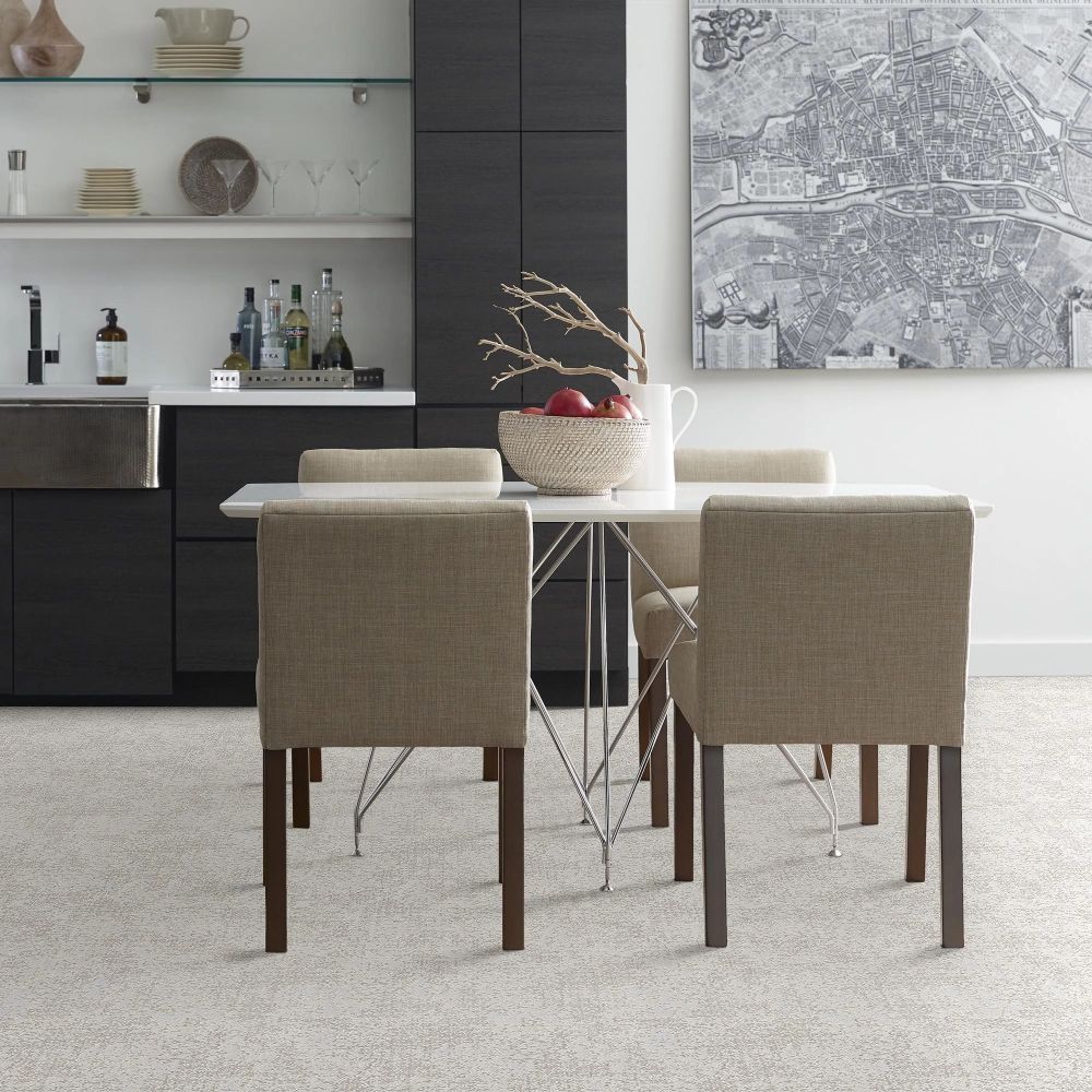 Modern dining space with off-white textured carpeting, a white rectangular table with a chrome base, and four beige fabric chairs.