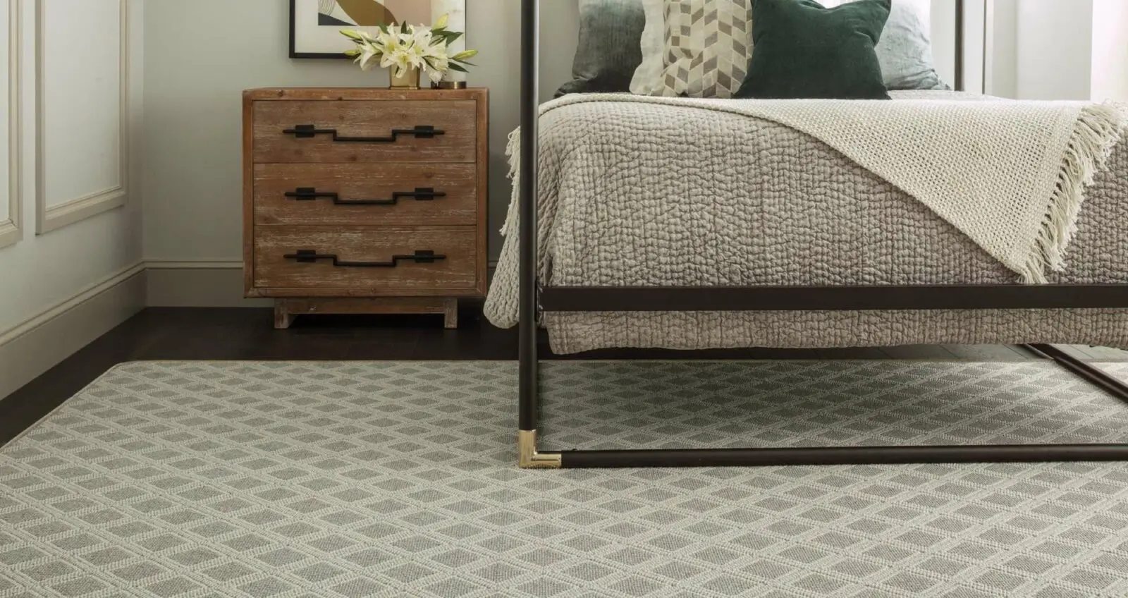 Grey and beige diamond pattern carpet in a bedroom beneath a dark metal bed frame.