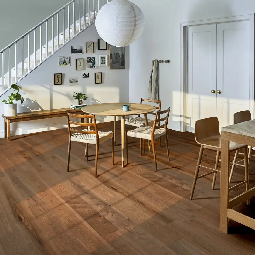 Modern dining area with a round wooden table over pecan hardwood flooring.