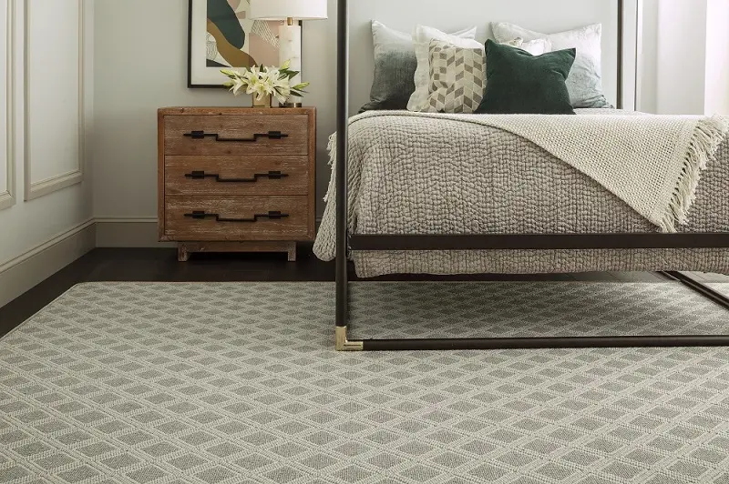 Light diamond-patterned carpet under a bed in a modern bedroom.