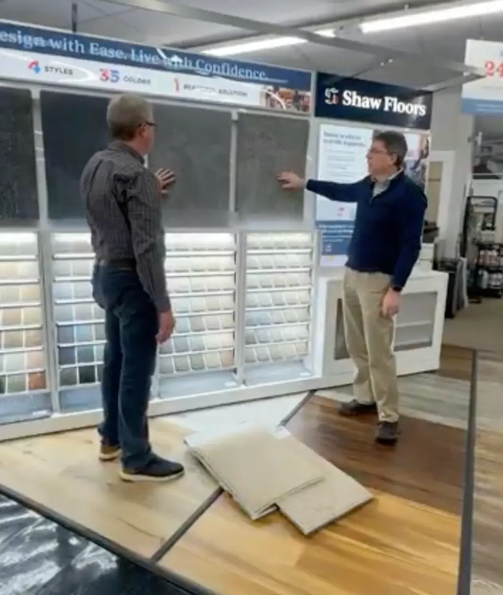 Two men comparing carpet samples at a Shaw Floors showroom display.