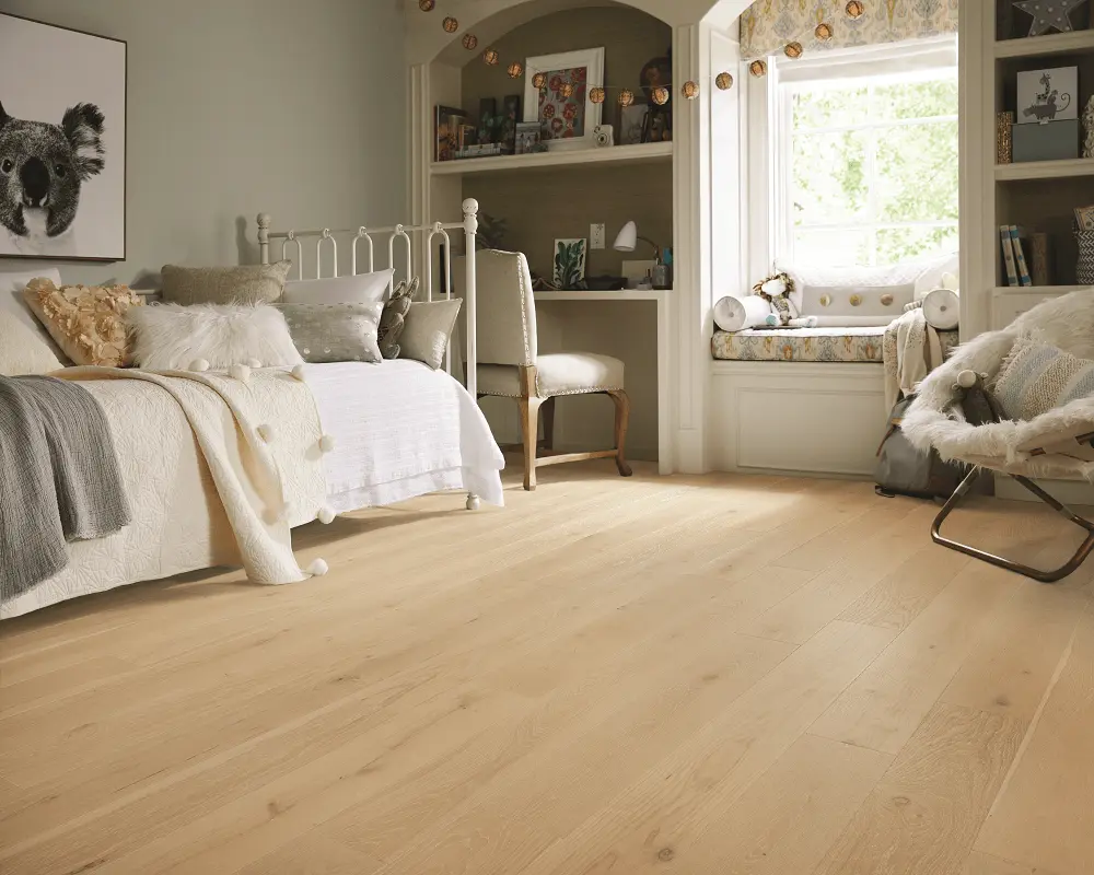 Light oak wood flooring in a bright child's bedroom with a white frame bed and window seat.