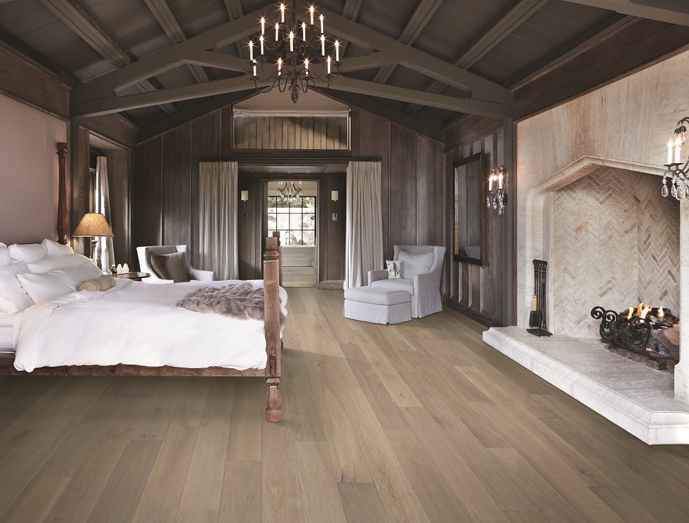 Rustic bedroom featuring a stone fireplace and light oak hardwood flooring.