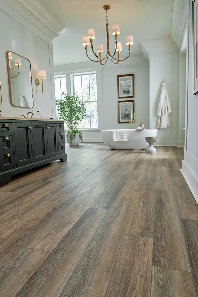 Medium brown wood-look flooring in a spacious bathroom with a freestanding tub and black vanity.
