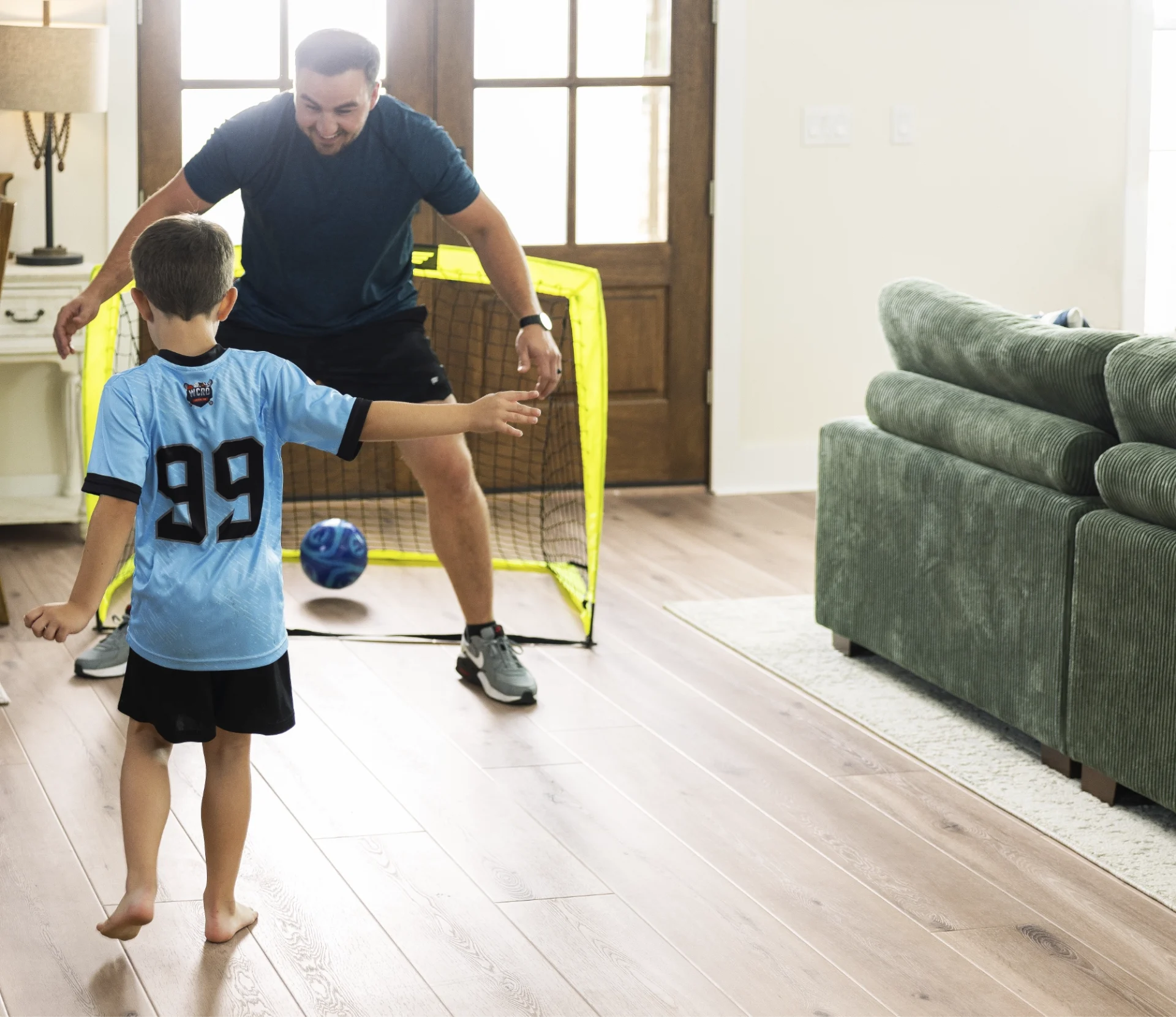Light oak wood-look flooring in a living room with a father and son playing indoor soccer.