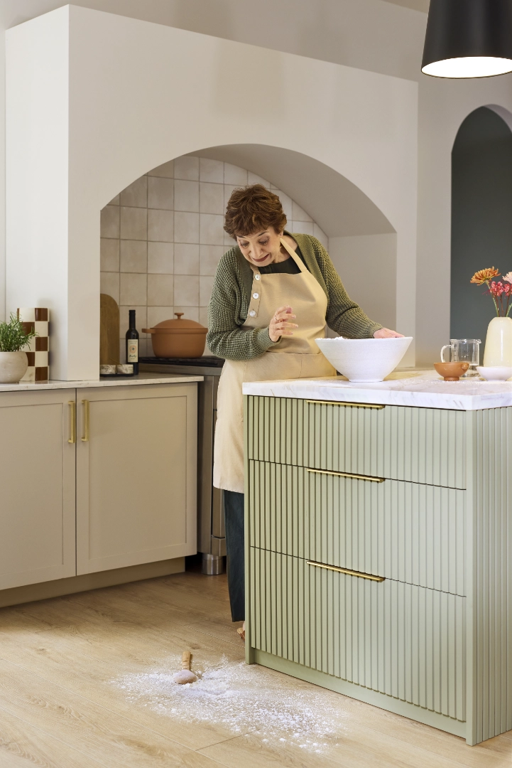 Woman looking at spilled flour on light oak kitchen flooring.