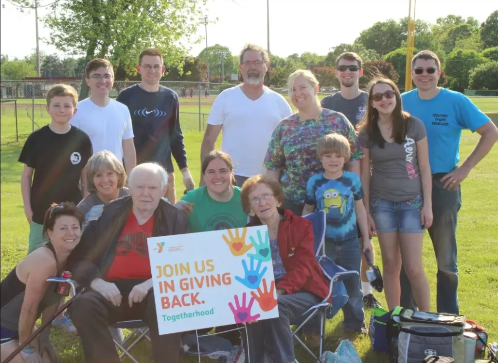YMCA Group Pic: Group of community volunteers gathered outdoors holding a YMCA "Giving Back" sign.